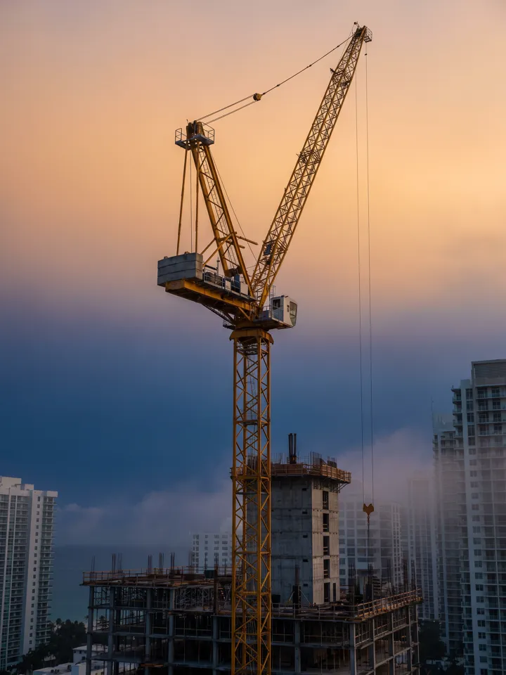 Tower crane lifting above a concrete frame under construction